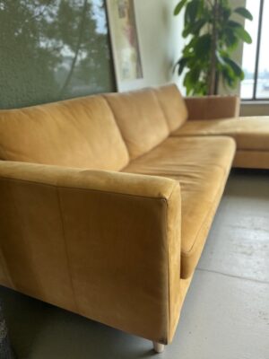 Front corner view of Coricraft mustard yellow leather sectional sofa in bright room