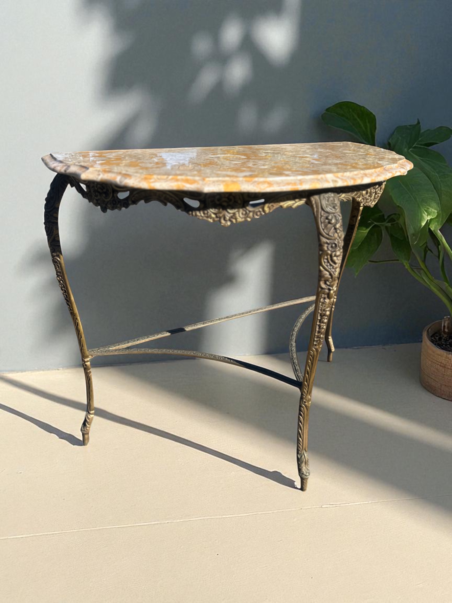 Ornate brass half-moon table with marble top