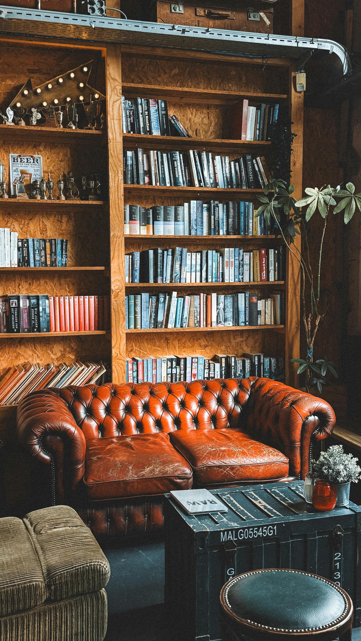 Warm library space with red leather sofa and wooden bookshelves in Tilburg, Netherlands.